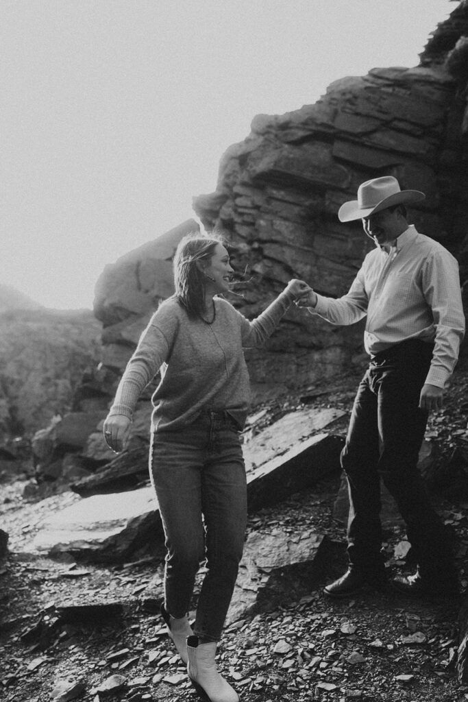 beautiful black and white photo of the couple holding hands walking on the mountain