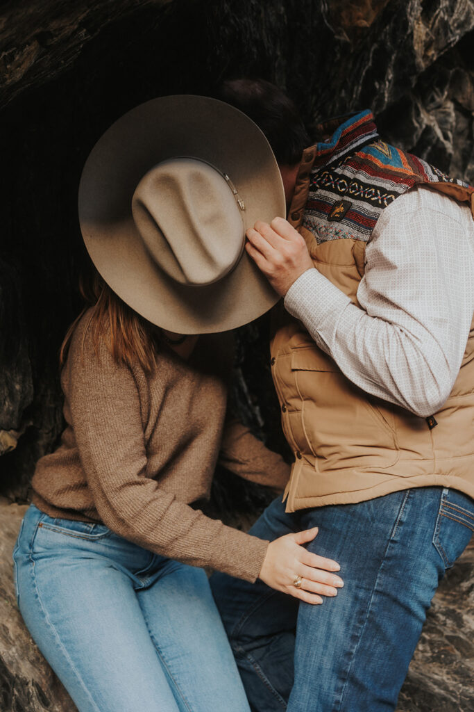 couple kissing and covering their face with a cowboy hat