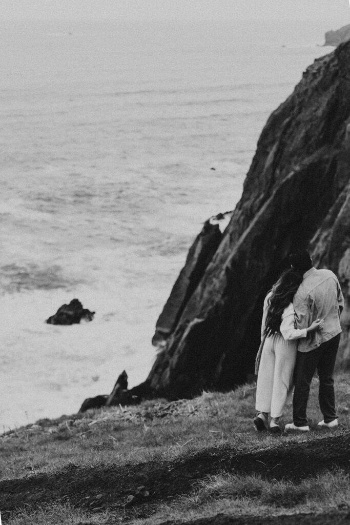 couple hugging looking at the ocean 