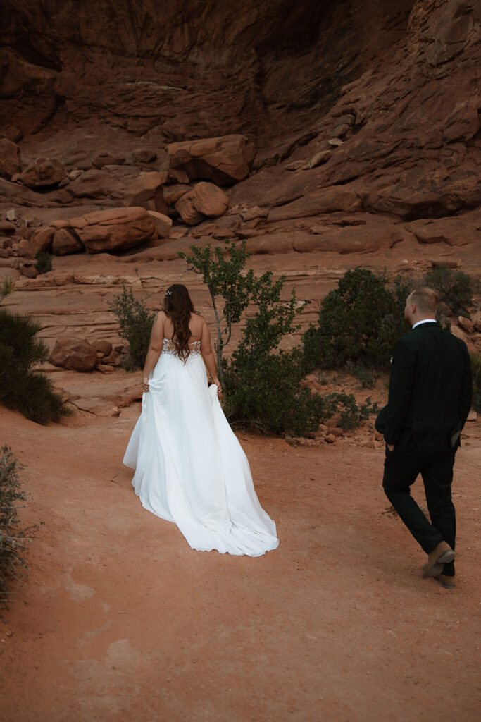 bride and groom walking around arches national park