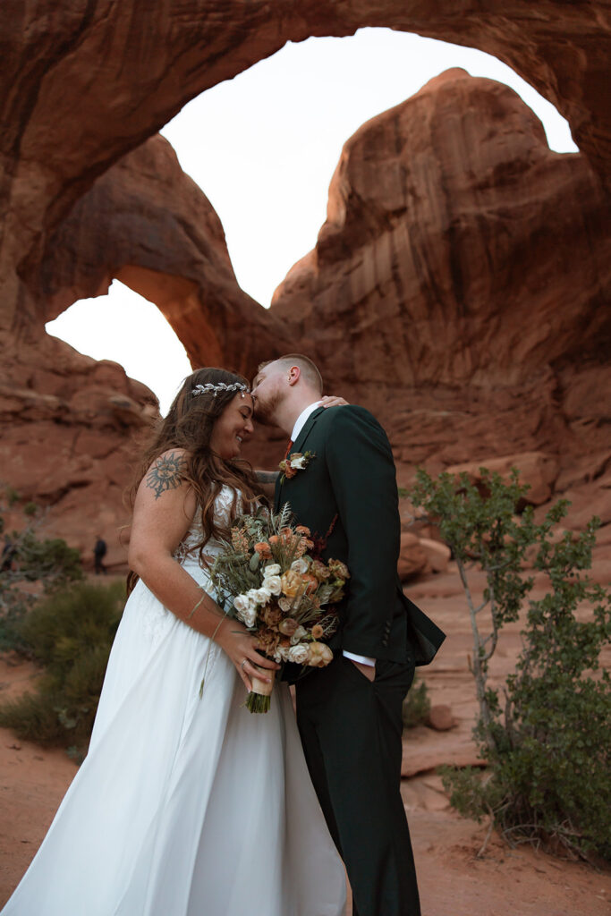 groom kissing the bride on the forehead 