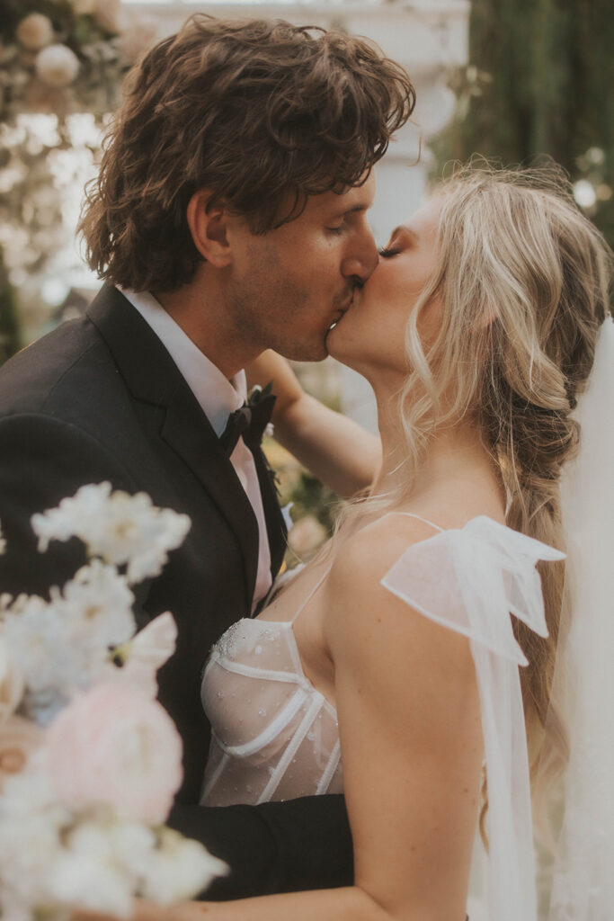 bride and groom kissing at their luxurious and adventurous wedding 