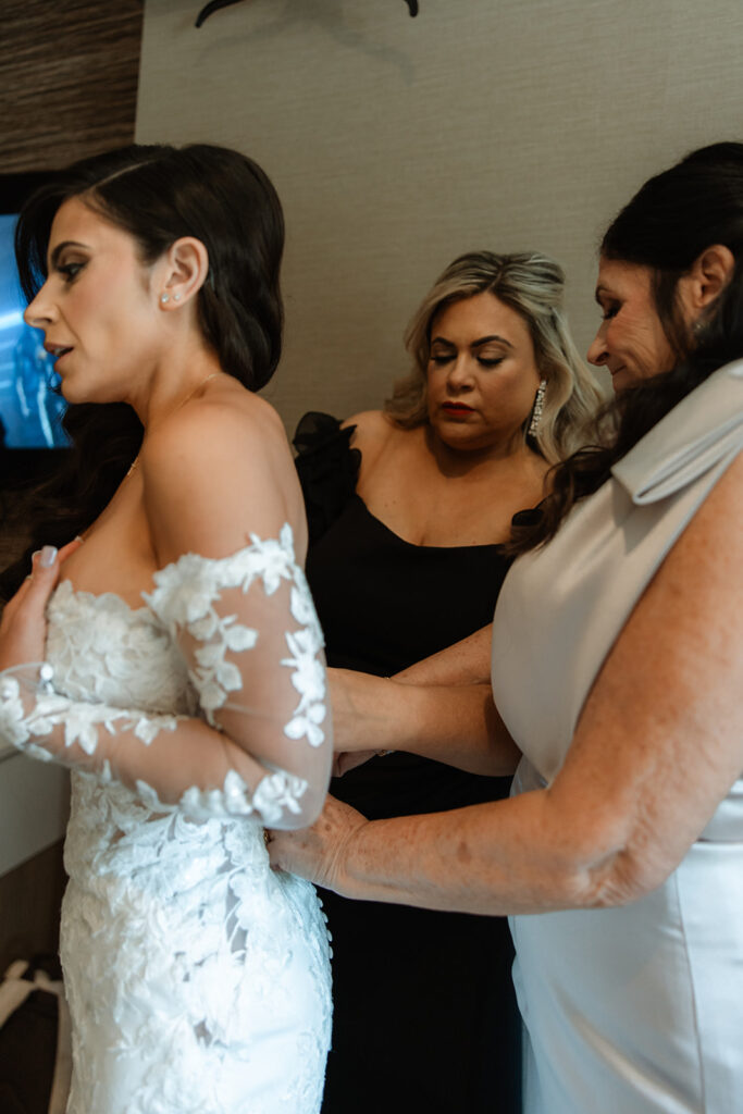 mother of the bride helping her with the wedding dress