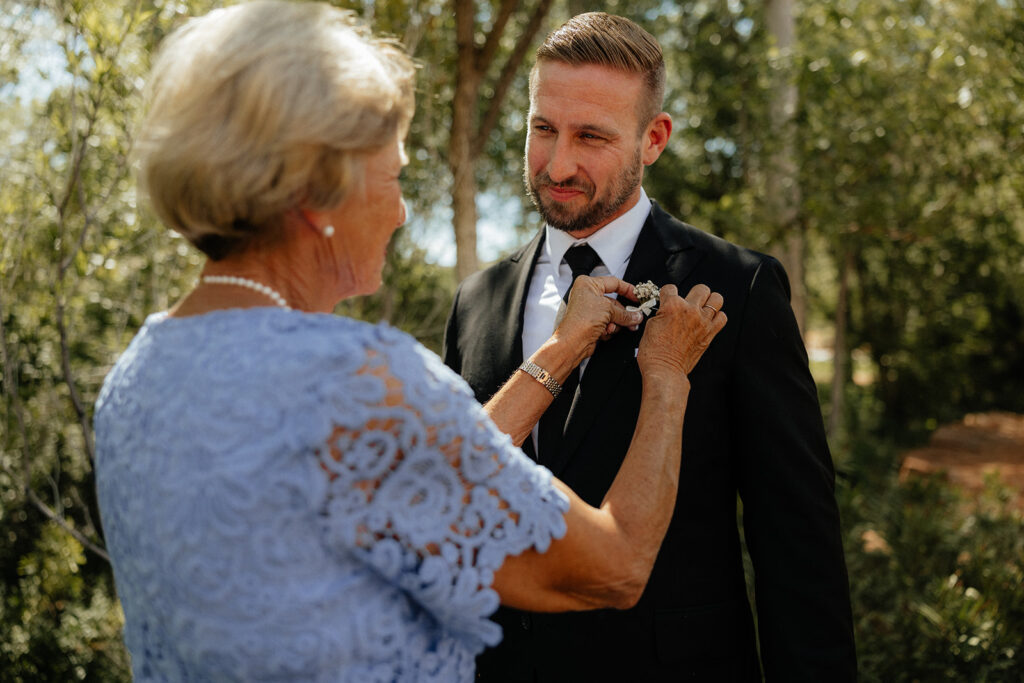 mother of the groom helping him get ready for the wedding ceremony