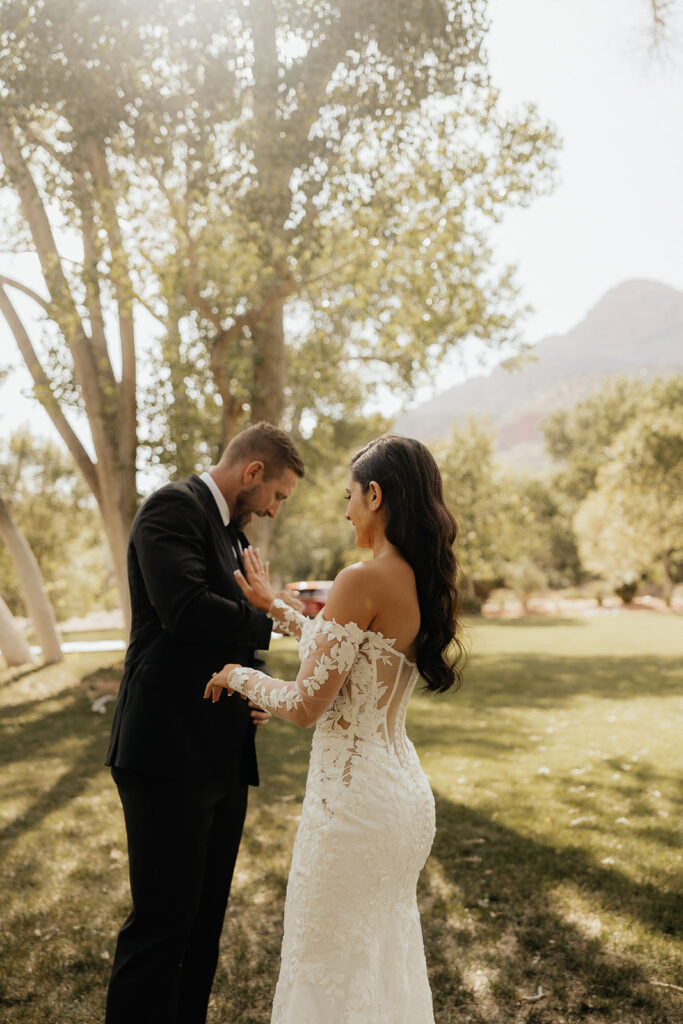 groom helping the bride with her wedding dress sleeve 