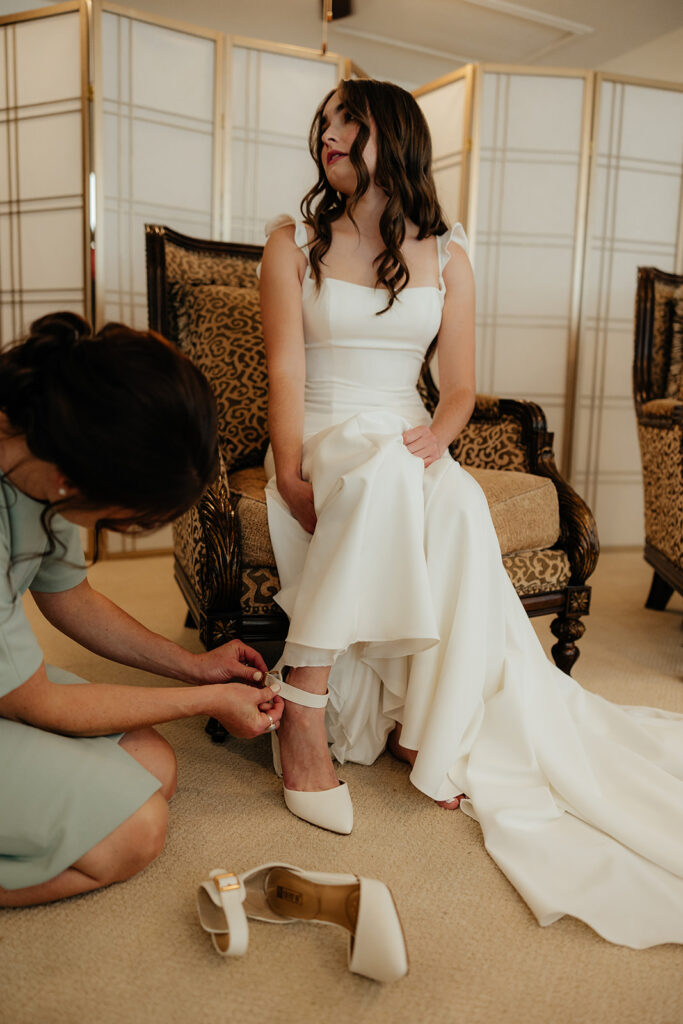 mother of the bride helping her with her wedding shoes
