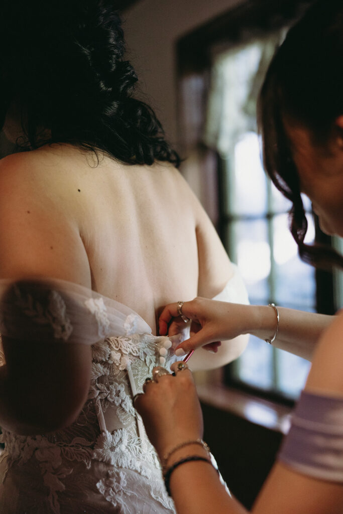 mother of the bride helping her with her wedding dress