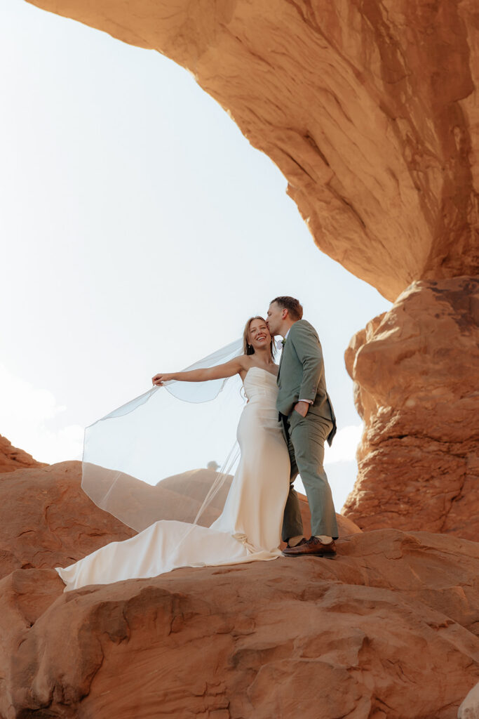 Groom, kissing the bride on the cheek