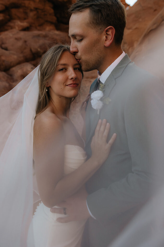 Groom, kissing the bride on the forehead