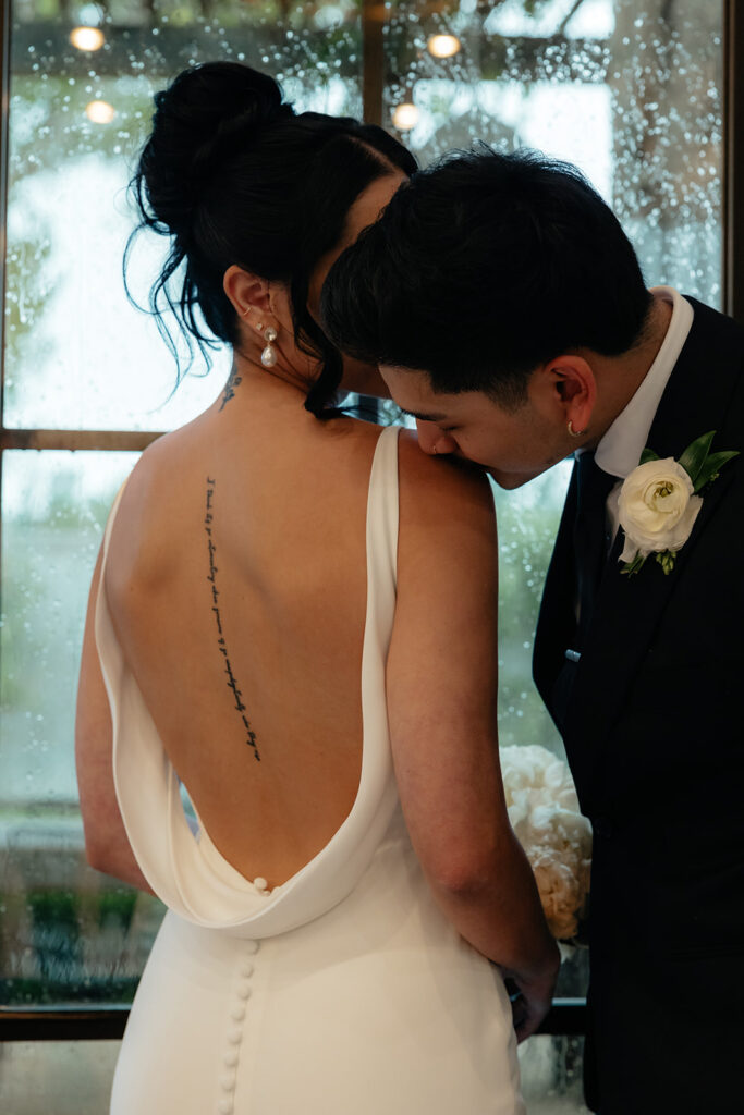 groom kissing the bride on the shoulder